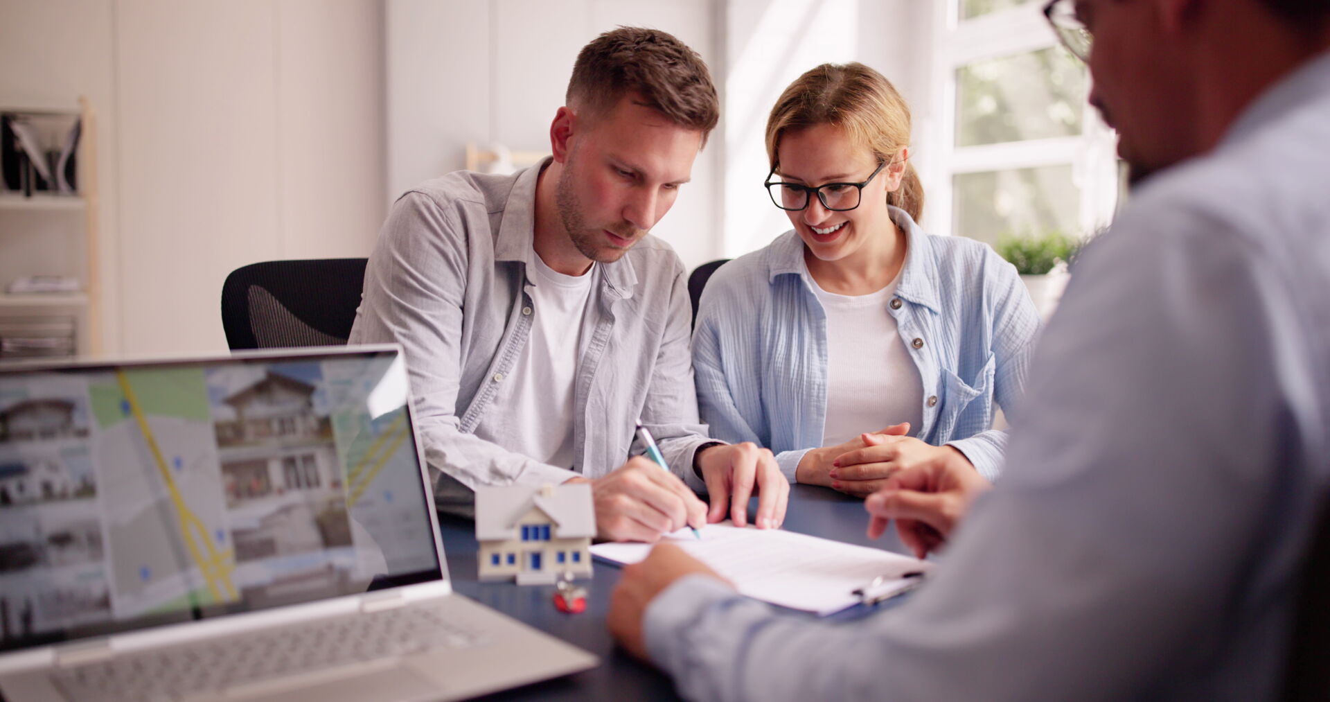 Junges Paar bei Unterzeichnung eines Immobilien-Kaufvertrages